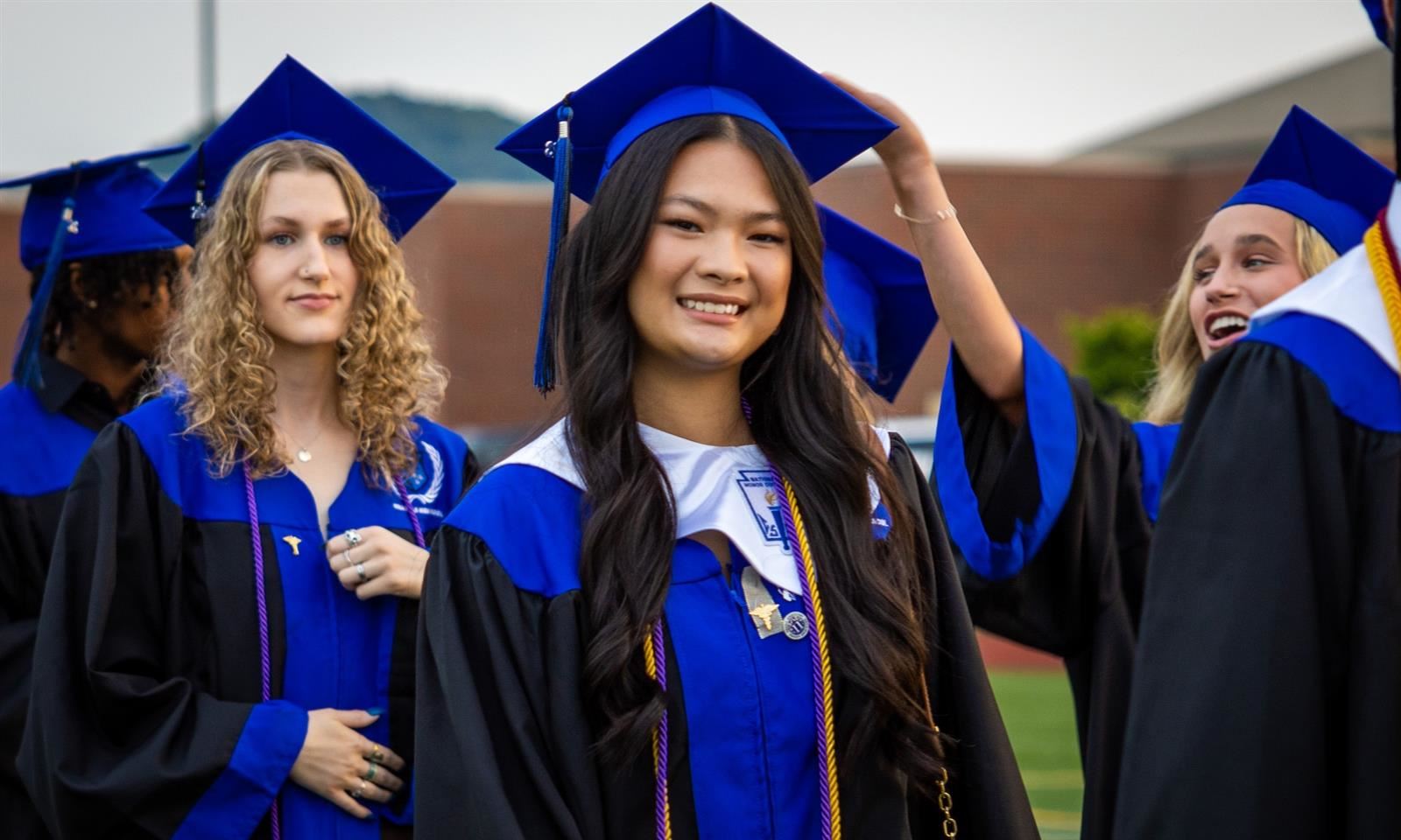 A girl in graduation robes smiles